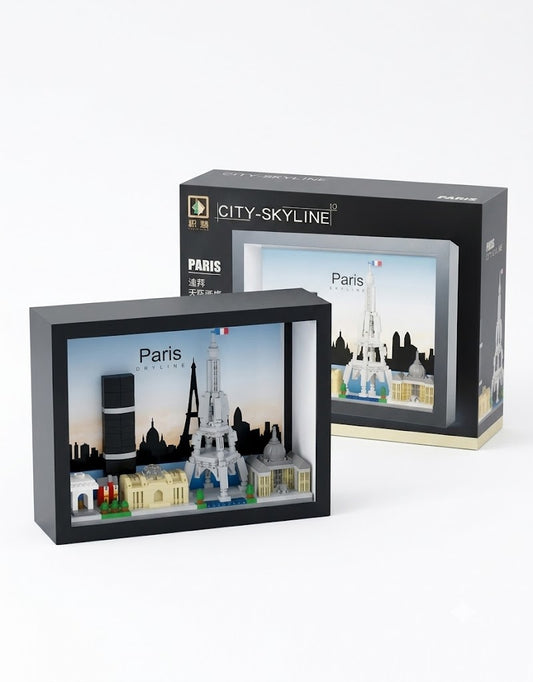 Assembled 3D Paris skyline micro building block model in a black shadow box frame with the Eiffel Tower next to retail packaging.