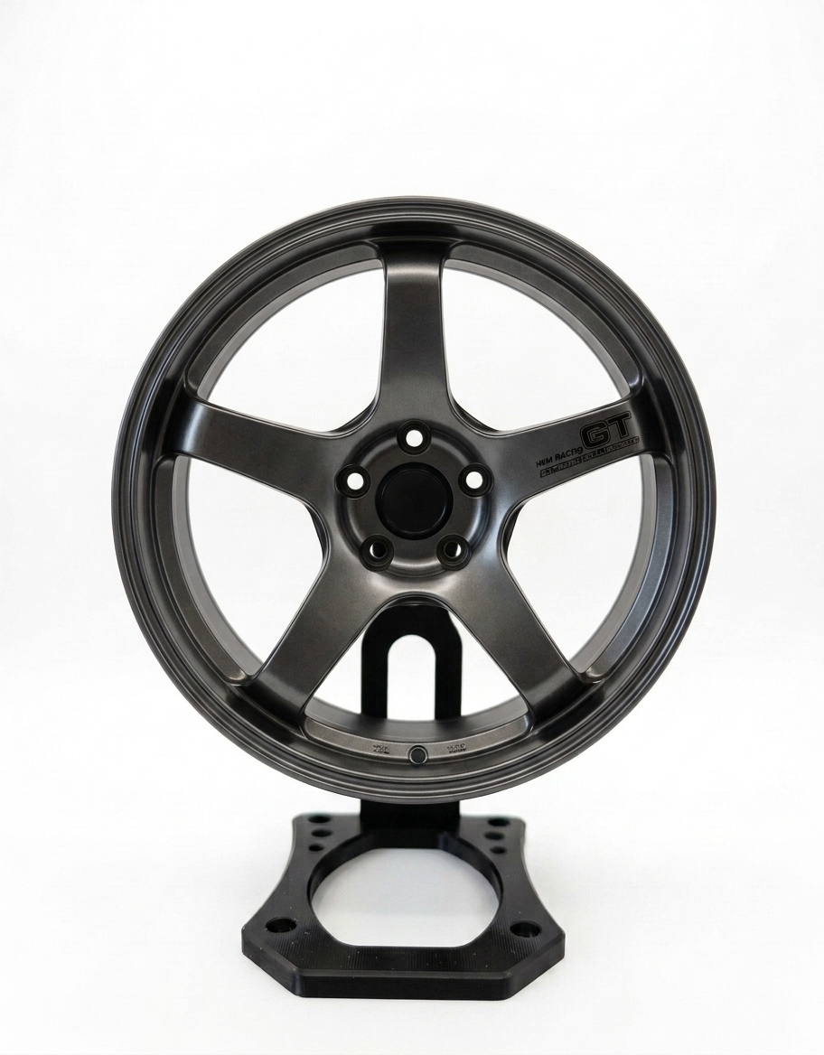 Front view of 10cm gunmetal 5-spoke miniature alloy rim mounted securely on black aluminum rotating desk stand.
