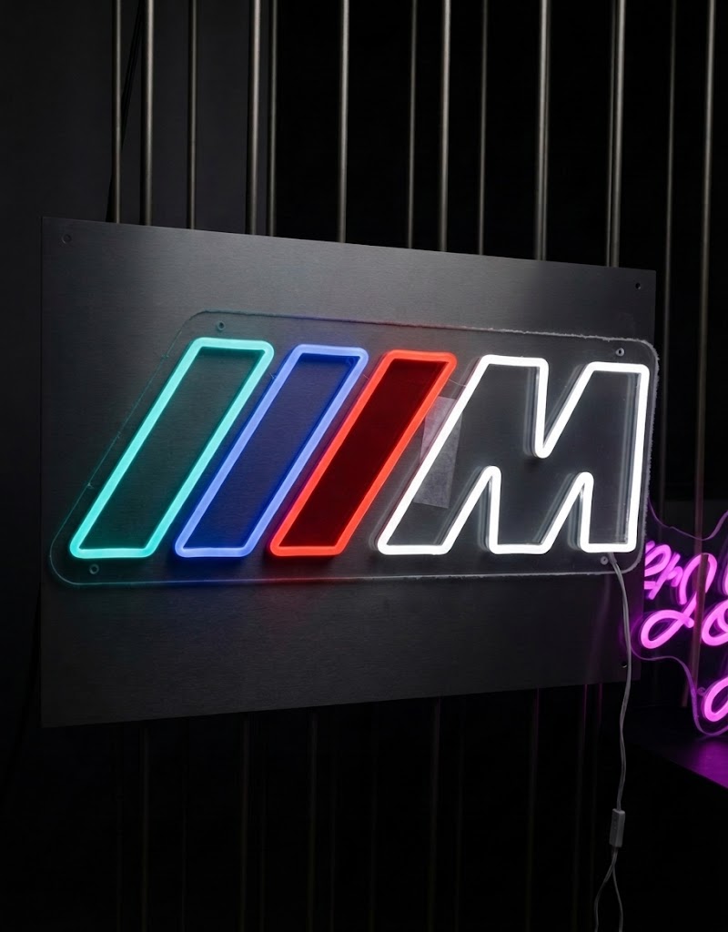 Close-up of glowing BMW M Performance LED neon sign mounted with inline dimmer switch cable.