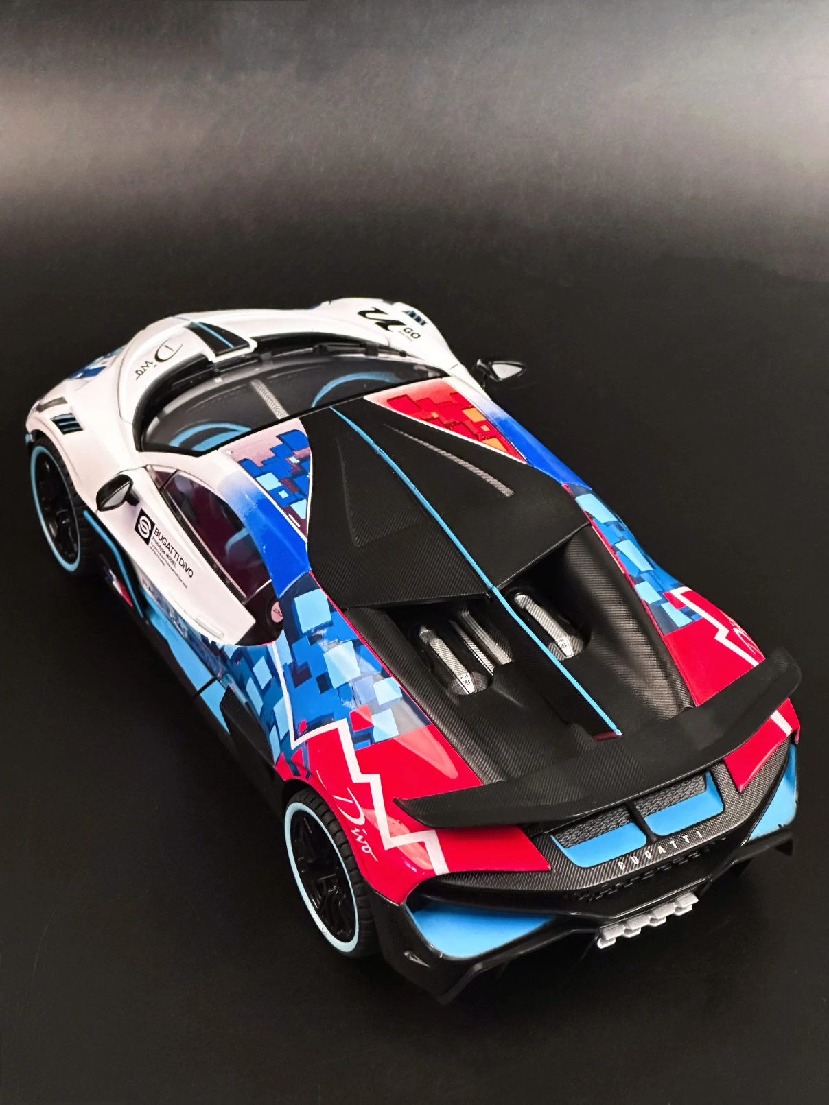 High-angle top view of 1:18 scale Bugatti Divo showing roofline aero fins, exposed engine bay detailing, and geometric graphics.