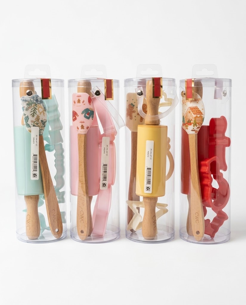Four-pack Christmas mini baking gift cylinders in mint green, pastel pink, butter yellow, and holiday red with rolling pins and spatulas.