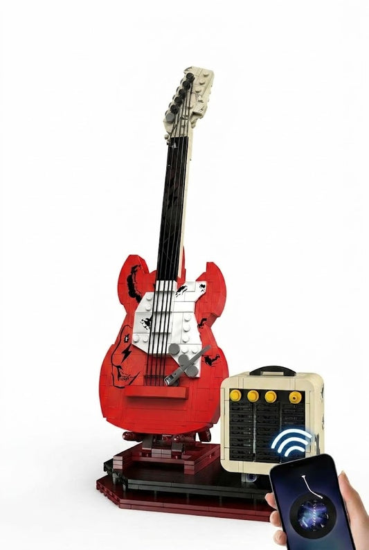 Assembled red electric rock guitar building block model on display stand beside functional mini amplifier Bluetooth speaker streaming music from a smartphone.