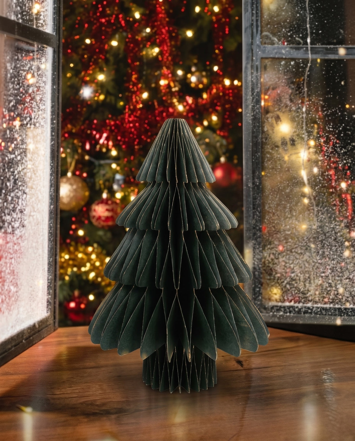 Deep forest green foldable 3D paper Christmas tree with gold-tipped edges displayed on a rustic tabletop, Christmas decoration Lebanon.