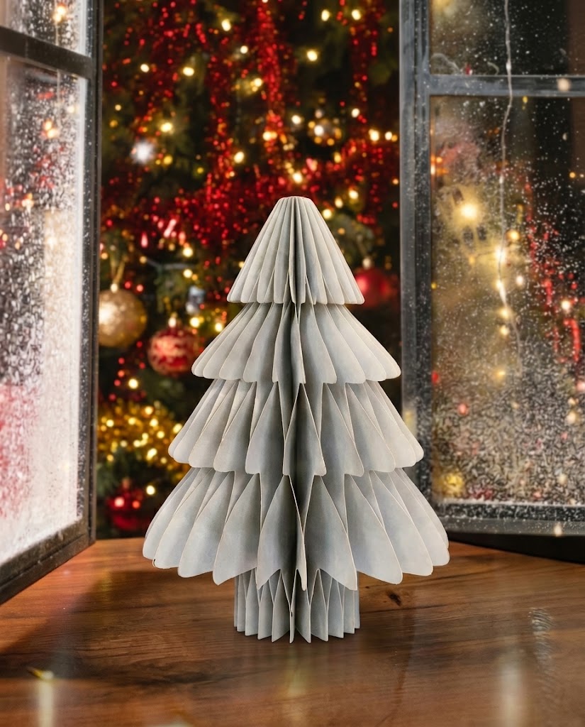 Minimalist ice blue and light grey pleated paper Christmas tree with subtle gold trim on a warm wooden windowsill.