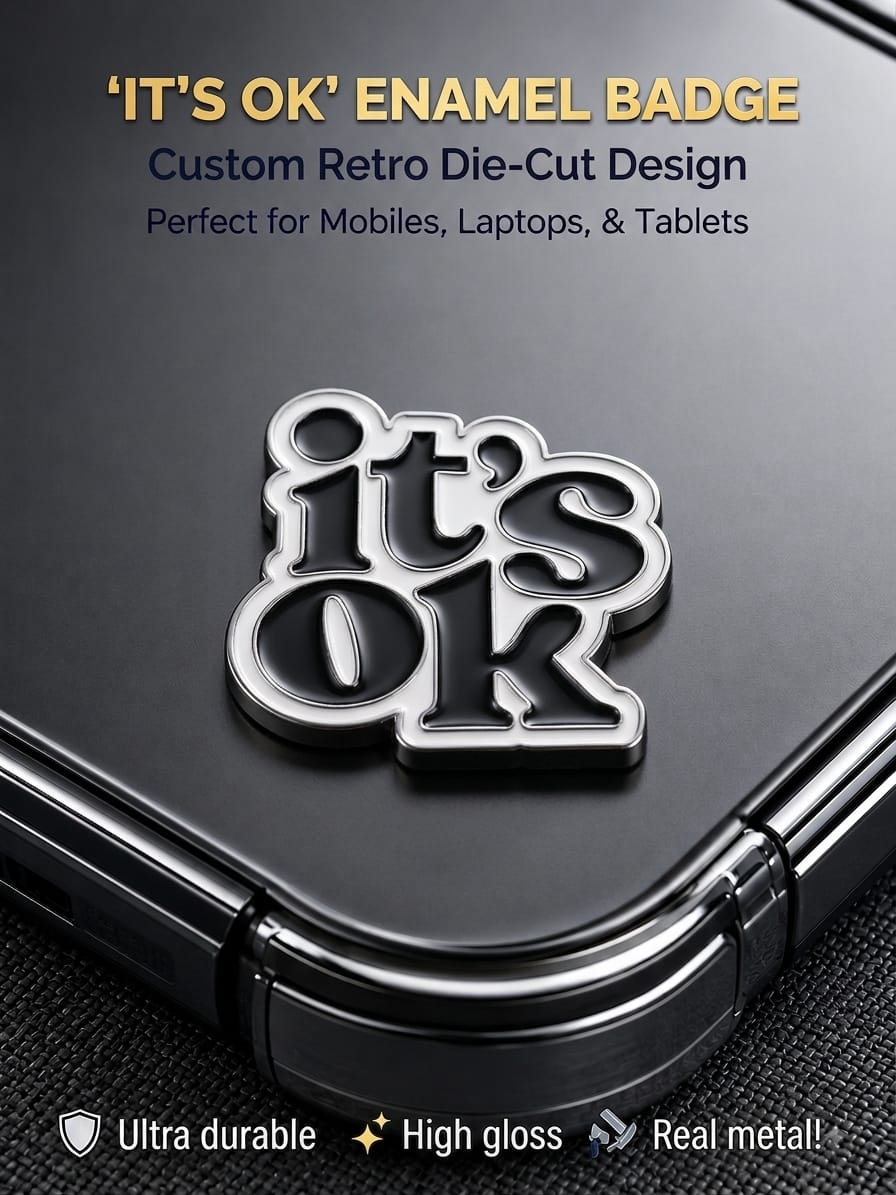 Black and silver retro die-cut "It's OK" metal enamel badge sticker applied to the back of a smartphone.