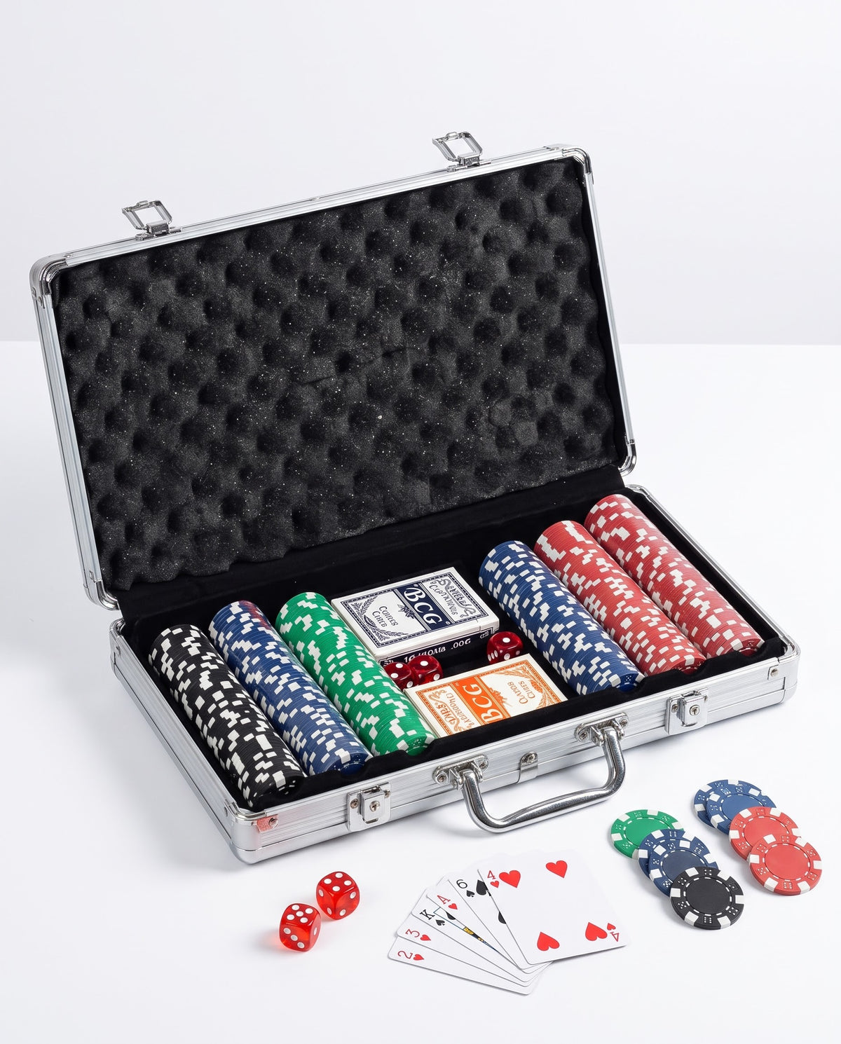Angled view of portable poker game set with multi-colored chips, BCG playing cards, and dice in a foam-padded metal case.