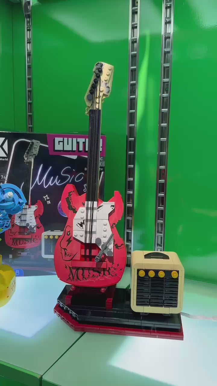 Assembled red rock guitar brick model and mini amplifier speaker showcased on an illuminated store display video.