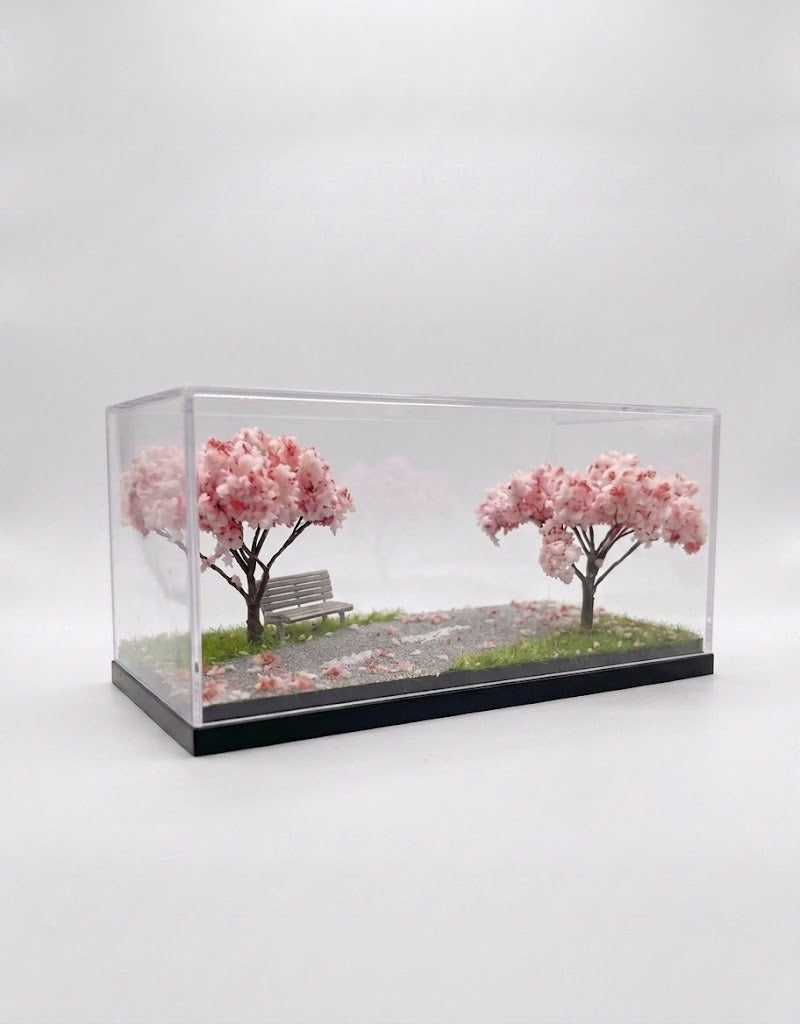 Handcrafted 1:64 scale sakura cherry blossom diorama base with park bench inside a clear acrylic dust display case.