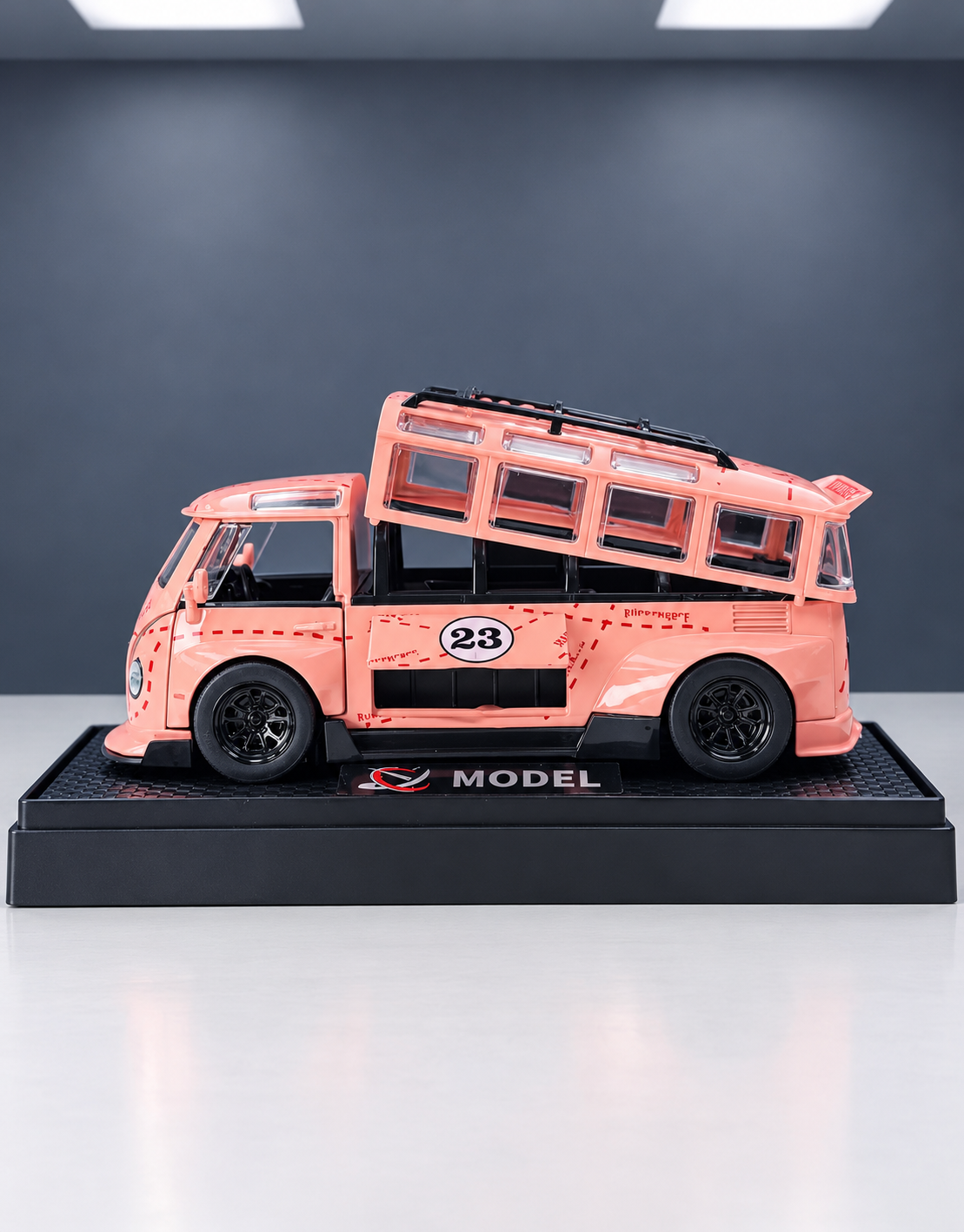 Side profile view of custom widebody pink VW race van scale model showing modular detachable roof shell and roll cage interior on display base.