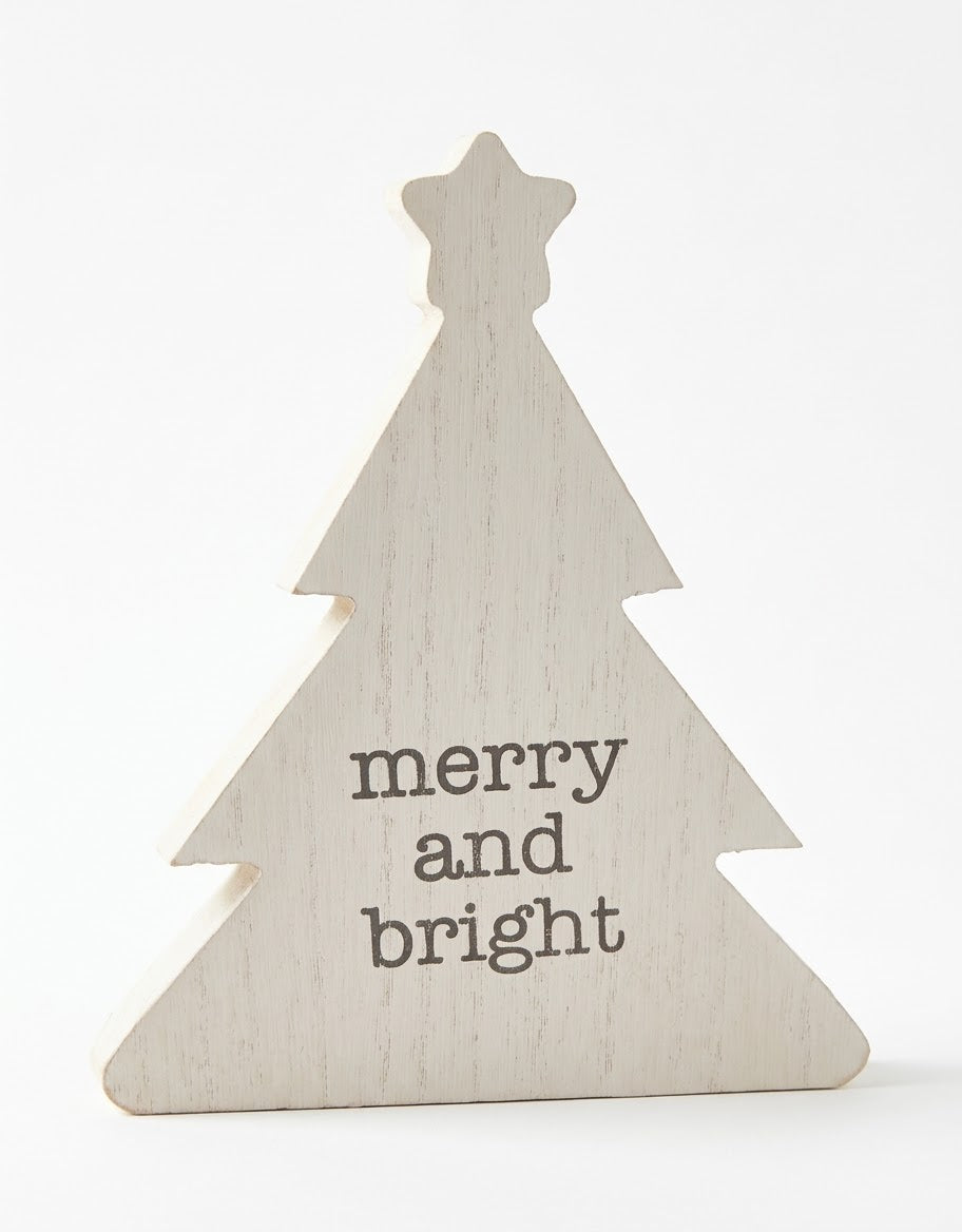 Freestanding whitewashed wooden Christmas tree tabletop plaque with a top star and "merry and bright" inscription on a white background.
